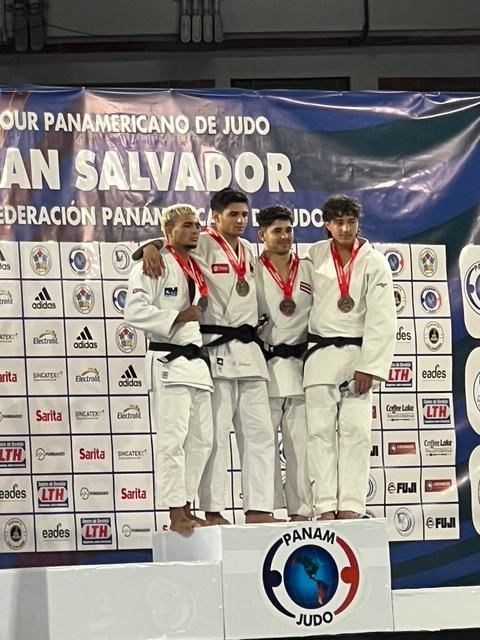 Four young judokas with medals on the podium at a Pan American judo tour event in San Salvador.