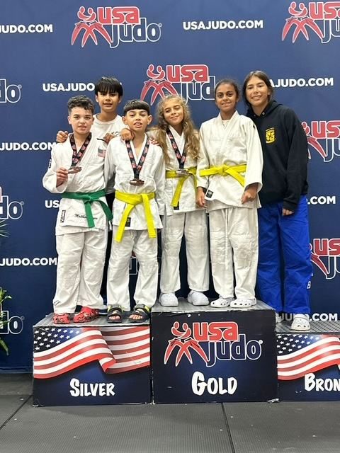 Young judokas with their medals on a USA Judo tournament podium.